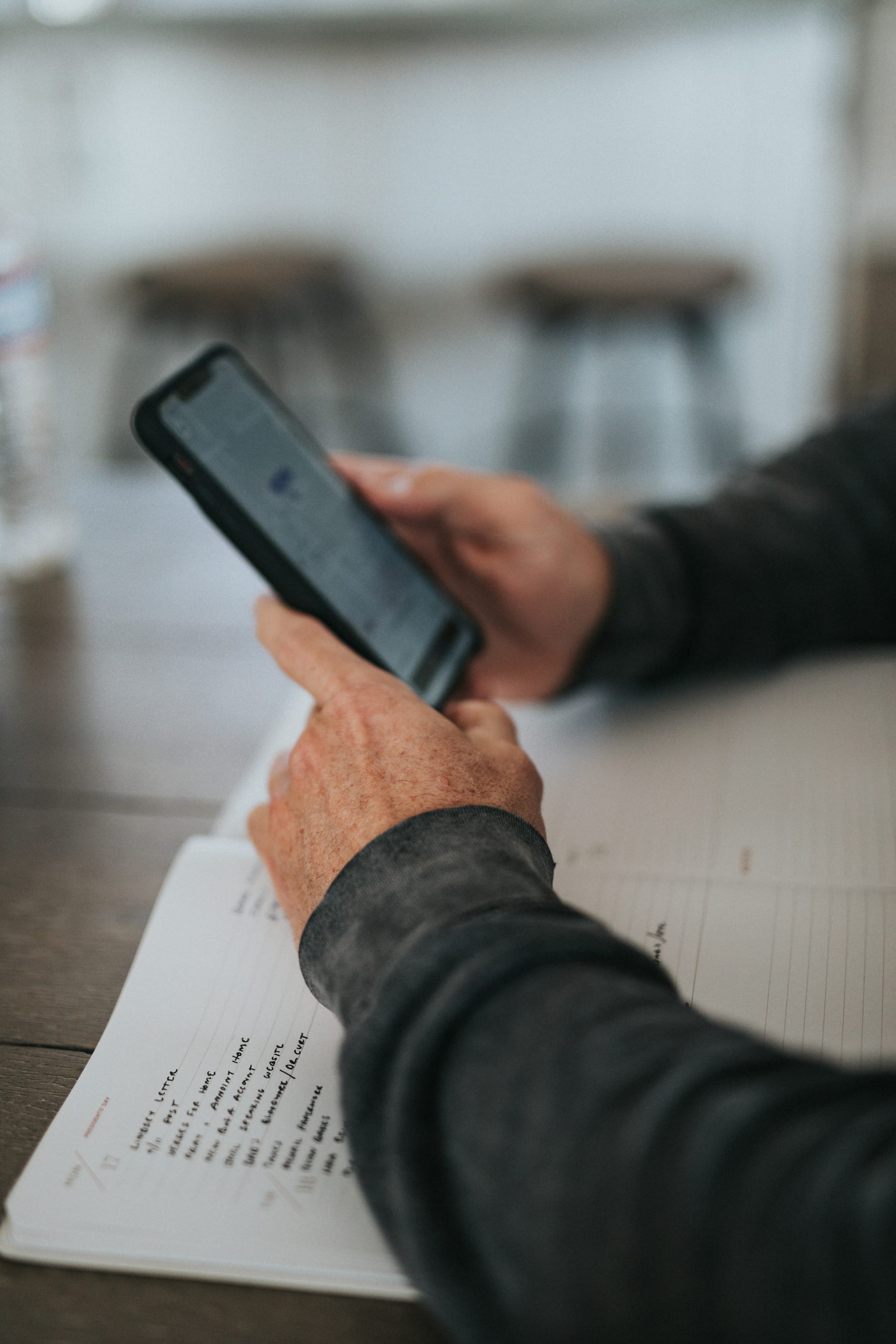 Mãos segurando um smartphone sobre uma agenda aberta